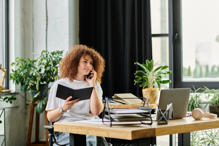 woman at home office desk, on phone with drapery and plants in background